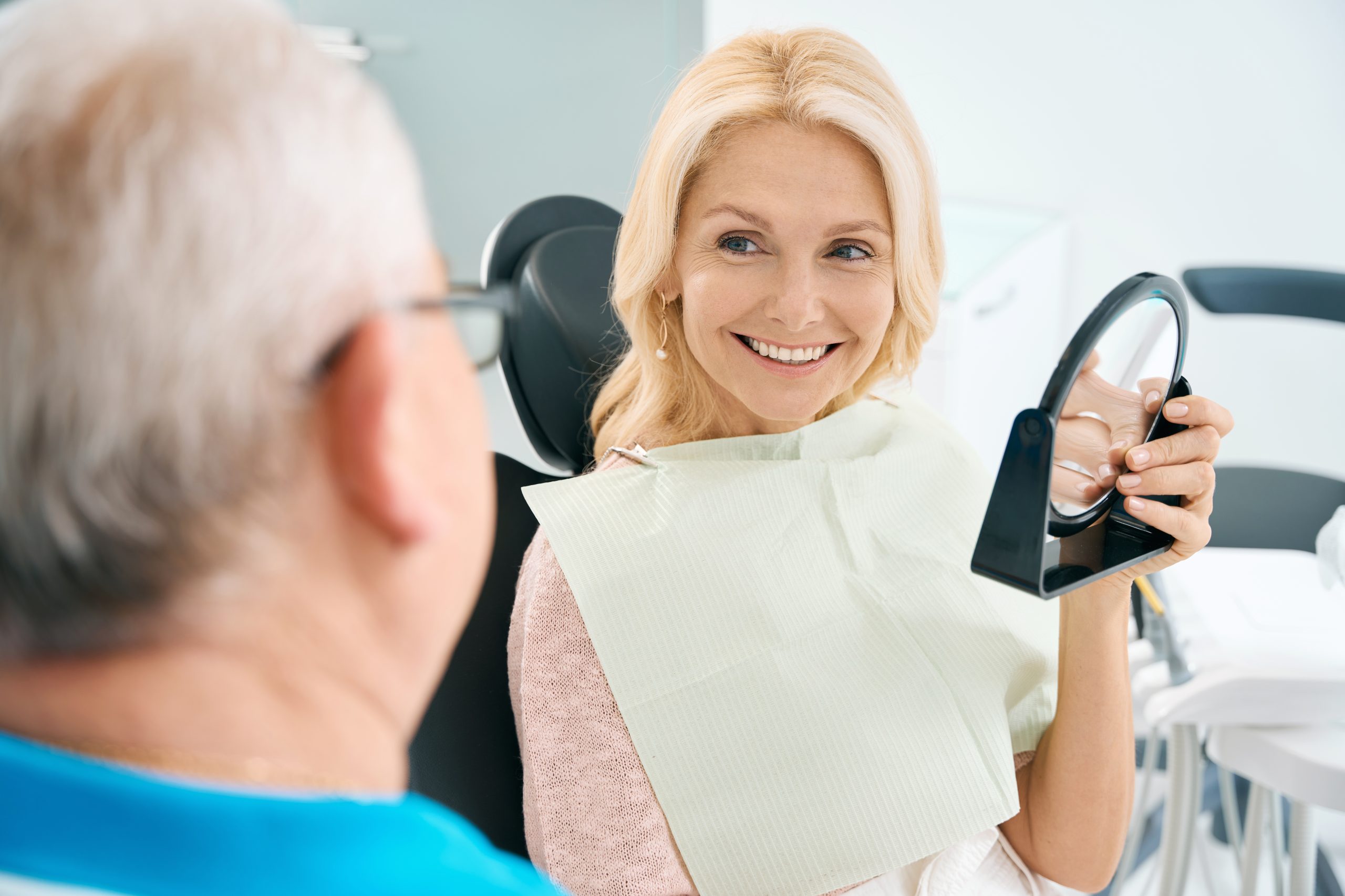 Beautiful woman is talking with dentist after the teeth treatment in clinic